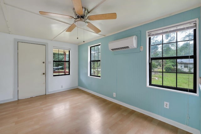 spare room featuring light hardwood / wood-style flooring, a wall unit AC, and ceiling fan