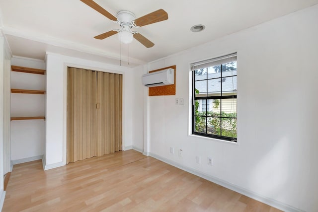 unfurnished bedroom featuring a wall mounted AC, ceiling fan, and light hardwood / wood-style flooring