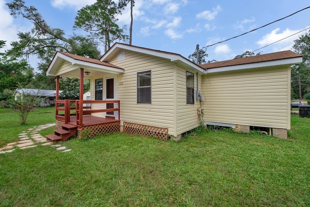 back of house featuring a lawn and a deck