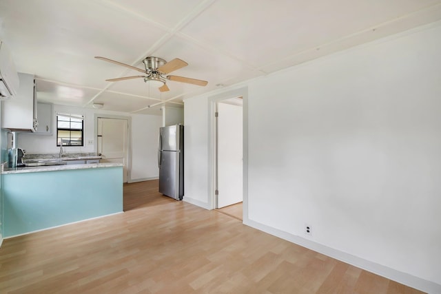 kitchen with appliances with stainless steel finishes, light wood-type flooring, coffered ceiling, sink, and white cabinets