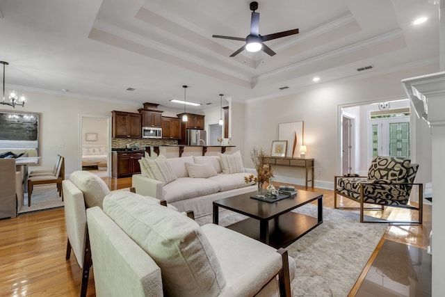3574 Strolling Way, Tallahassee, FL 32311 - living room with a tray ceiling, ceiling fan, a chandelier, light wood-type flooring, and ornamental molding