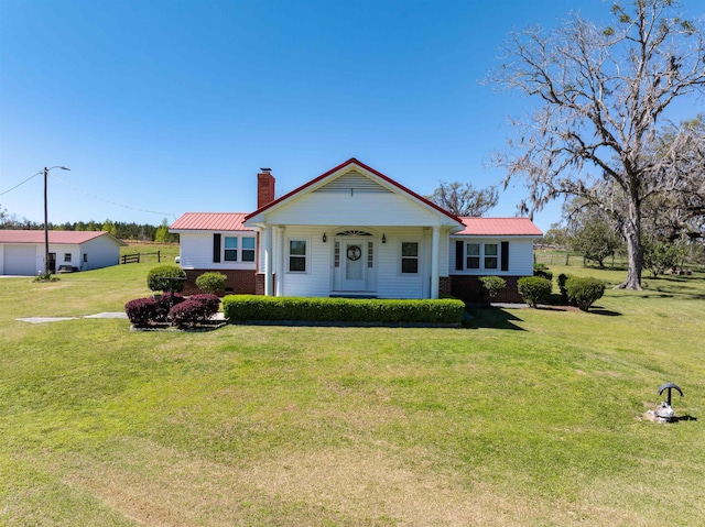 511 SW Sundown Creek Rd, Madison, FL 32340 - view of front of home featuring a chimney, a front yard, brick siding, and metal roof