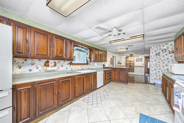 511 SW Sundown Creek Rd, Madison, FL 32340 - kitchen with ceiling fan, wallpapered walls, white appliances, a drop ceiling, and a peninsula