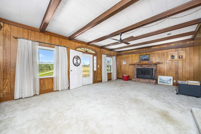 511 SW Sundown Creek Rd, Madison, FL 32340 - unfurnished living room with beamed ceiling, wood walls, a brick fireplace, ceiling fan, and healthy amount of natural light