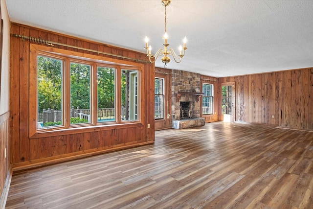 unfurnished living room featuring a wealth of natural light, hardwood / wood-style floors, and a notable chandelier