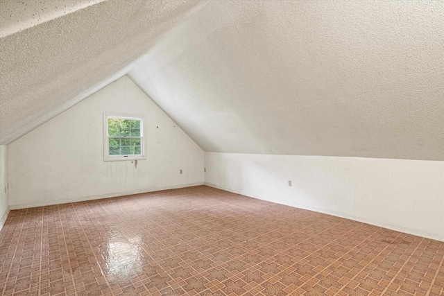 additional living space with a textured ceiling and lofted ceiling