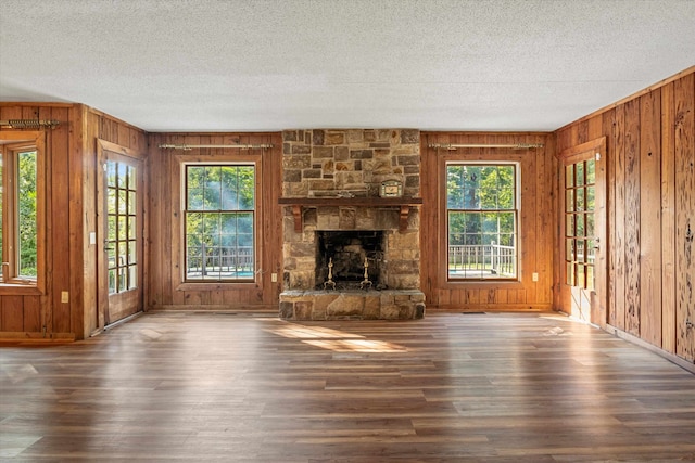 unfurnished living room featuring dark wood-type flooring, a wealth of natural light, a textured ceiling, and a fireplace