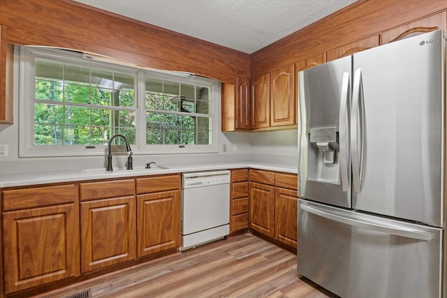 kitchen with dishwasher, light hardwood / wood-style flooring, a healthy amount of sunlight, and stainless steel fridge