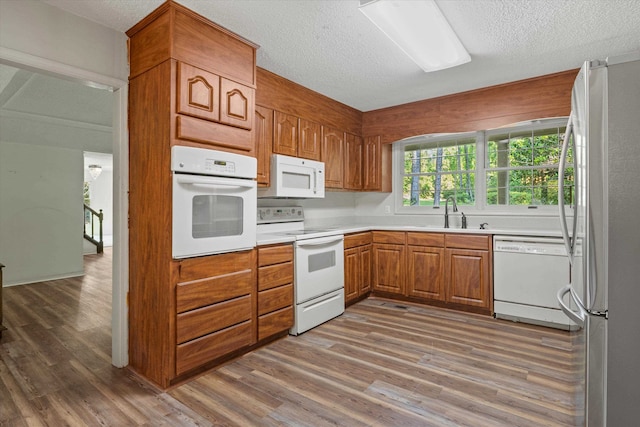 kitchen featuring a textured ceiling, wood-type flooring, sink, and white appliances