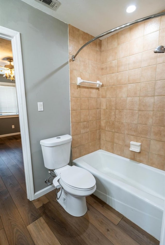 bathroom featuring toilet, tiled shower / bath, and wood-type flooring