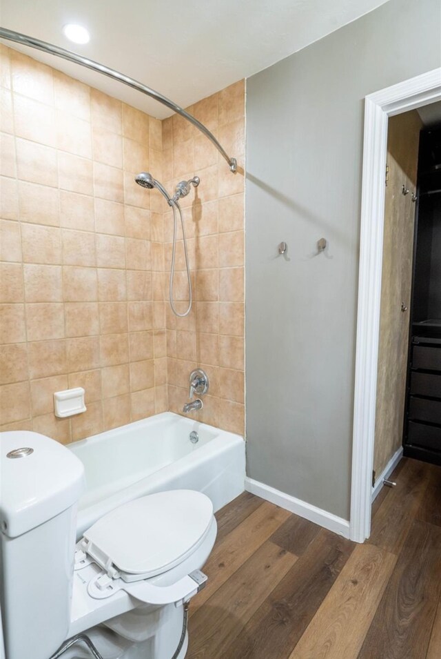 bathroom featuring toilet, tiled shower / bath combo, and hardwood / wood-style floors