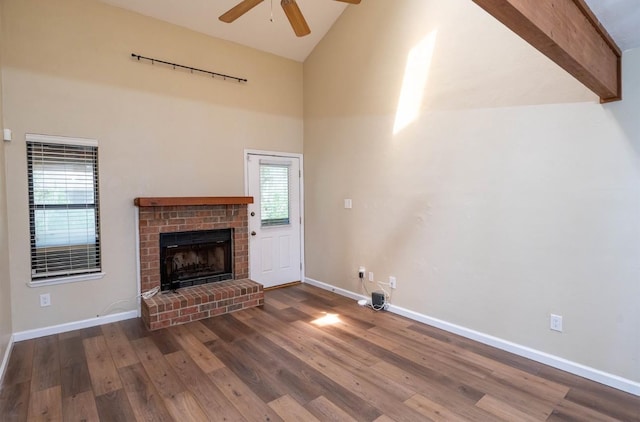 unfurnished living room featuring a fireplace, plenty of natural light, dark wood-type flooring, and beamed ceiling