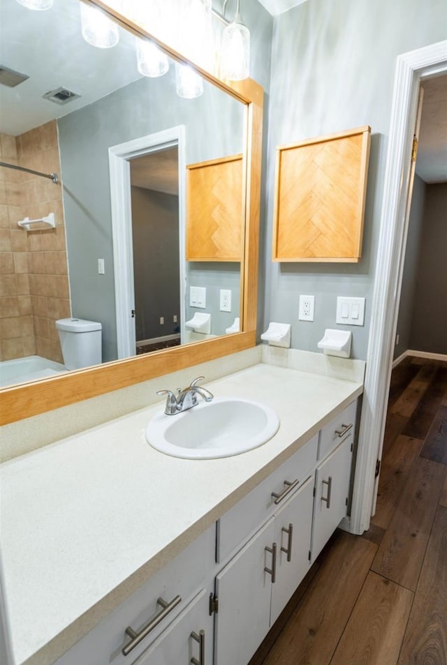 full bathroom featuring wood-type flooring, vanity, toilet, and tiled shower / bath combo