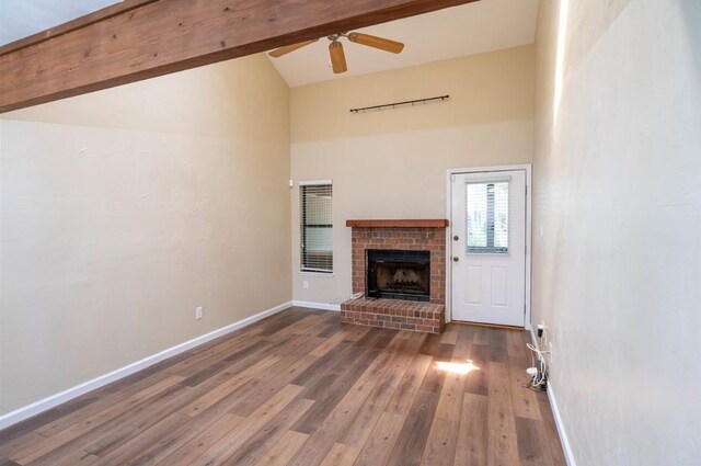 unfurnished living room featuring a brick fireplace, hardwood / wood-style flooring, high vaulted ceiling, beamed ceiling, and ceiling fan