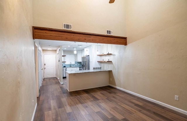 kitchen featuring stainless steel appliances, dark hardwood / wood-style flooring, white cabinets, kitchen peninsula, and sink