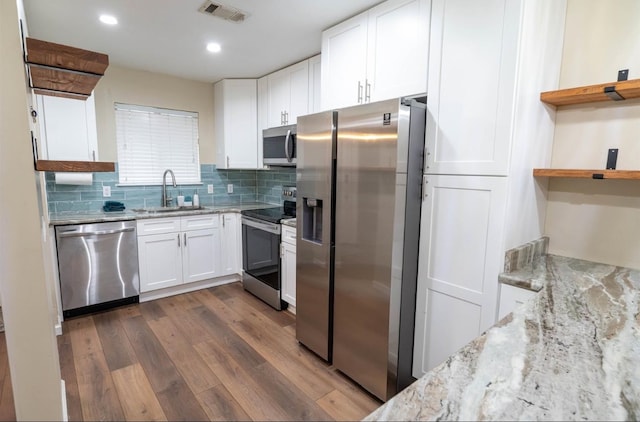 kitchen featuring stainless steel appliances, dark hardwood / wood-style floors, light stone countertops, sink, and white cabinets