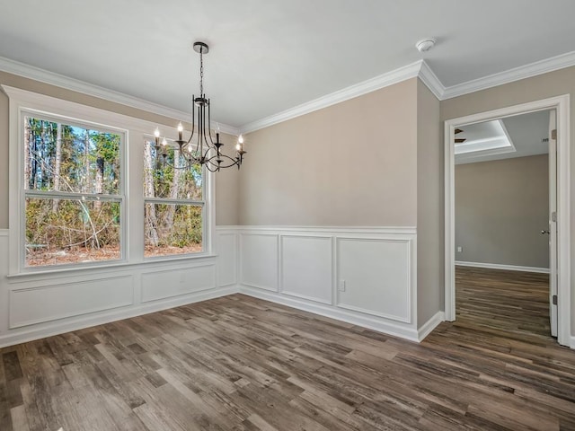 unfurnished dining area featuring dark hardwood / wood-style flooring, a chandelier, and crown molding