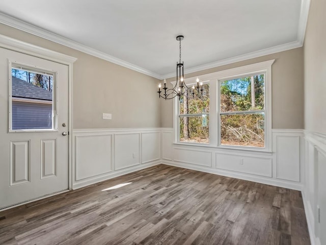 unfurnished dining area with ornamental molding, hardwood / wood-style flooring, and a chandelier