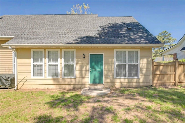bungalow-style house with a front yard, a shingled roof, fence, and entry steps