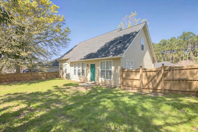 back of property with a fenced backyard, a shingled roof, and a lawn