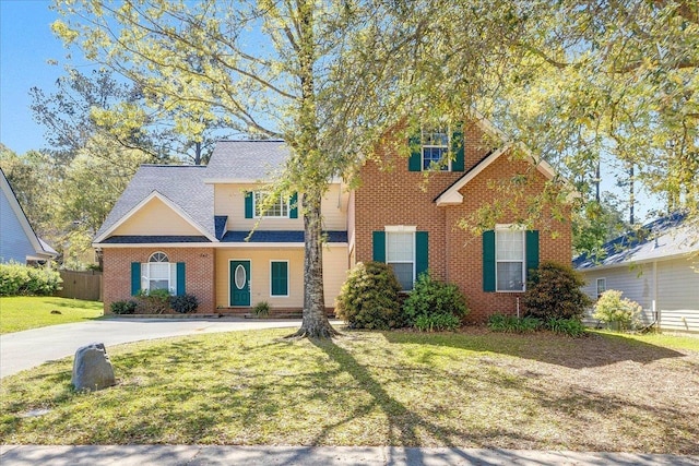 view of front of home with brick siding, driveway, fence, and a front lawn