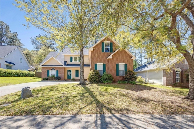 traditional-style house with brick siding, driveway, and a front lawn