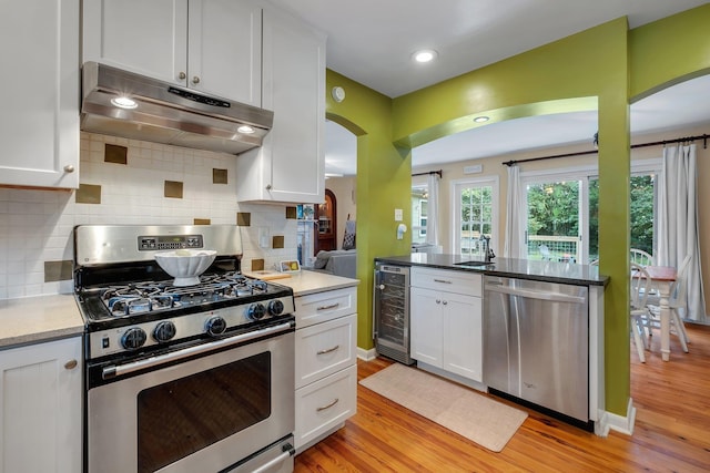 kitchen with white cabinetry, appliances with stainless steel finishes, and beverage cooler