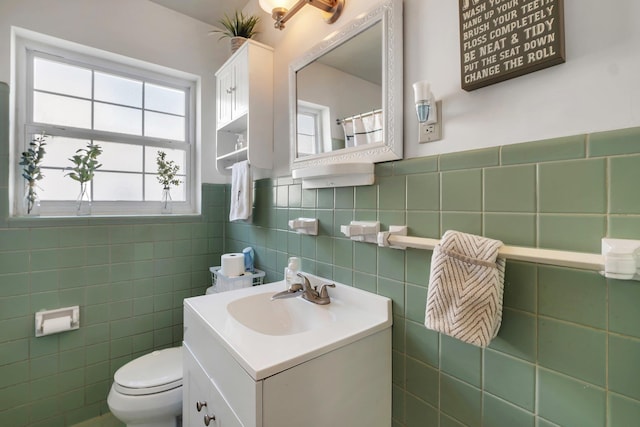 bathroom featuring vanity, tile walls, and toilet