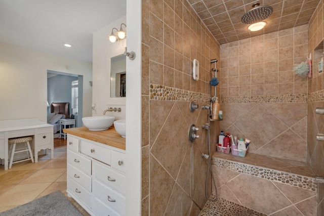 bathroom featuring a tile shower, vanity, and tile patterned floors