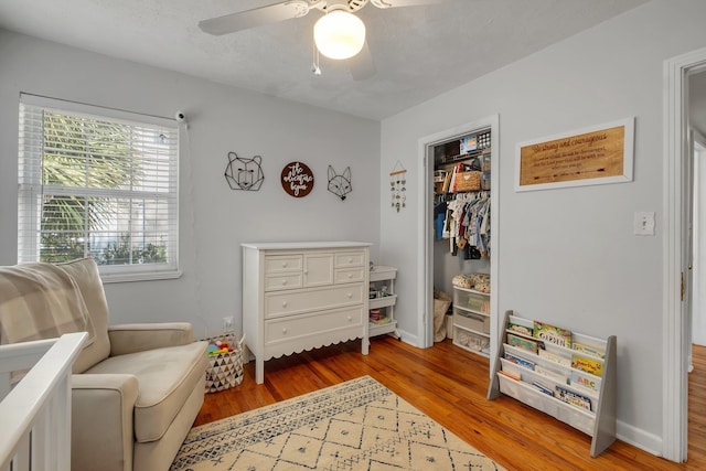 living area featuring ceiling fan, light hardwood / wood-style flooring, and a textured ceiling