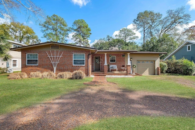 single story home featuring a garage, covered porch, and a front yard