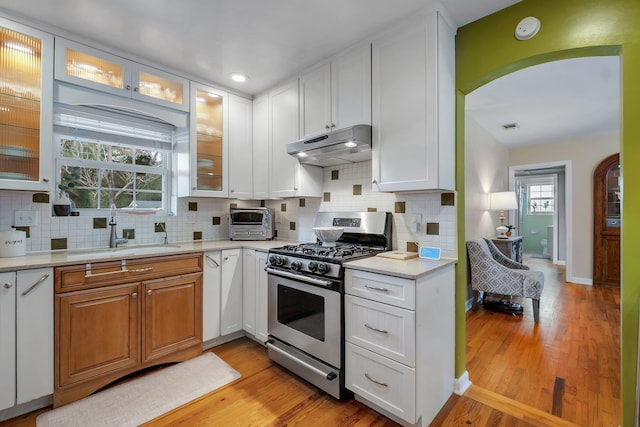 kitchen featuring sink, light hardwood / wood-style floors, gas stove, and white cabinets