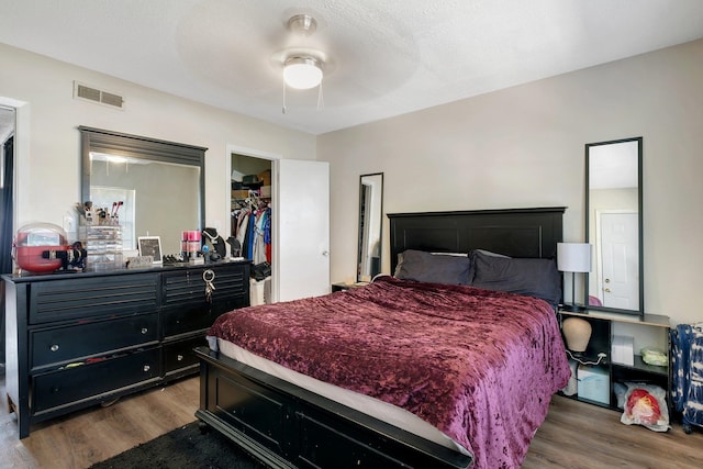 bedroom featuring a closet, a spacious closet, a textured ceiling, dark hardwood / wood-style flooring, and ceiling fan