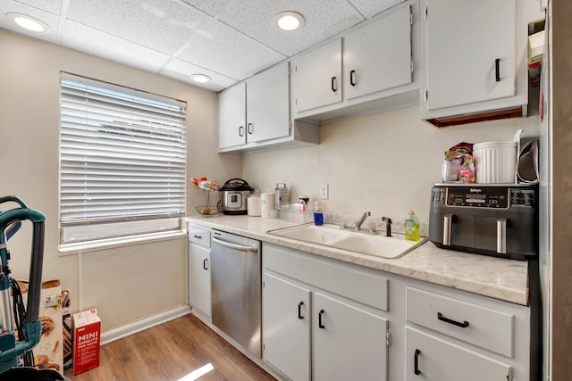 kitchen featuring light hardwood / wood-style floors, white cabinetry, sink, a paneled ceiling, and dishwasher