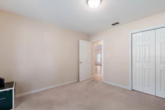 unfurnished bedroom featuring a closet and light colored carpet