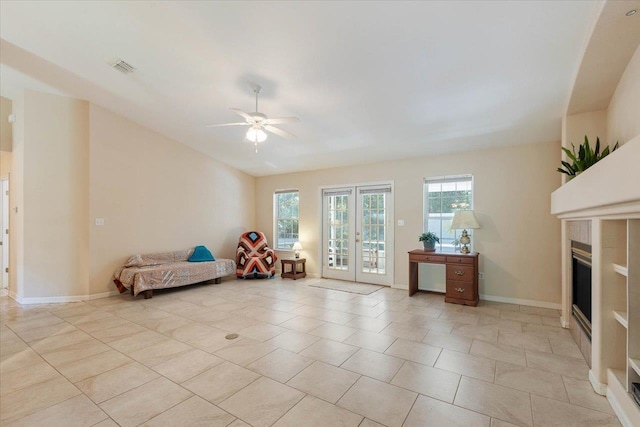 unfurnished room featuring french doors, ceiling fan, a tile fireplace, and light tile patterned floors