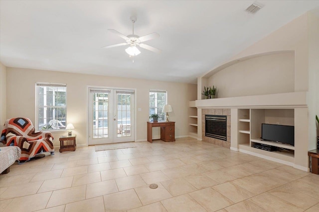 unfurnished living room with built in features, french doors, light tile patterned floors, a tiled fireplace, and ceiling fan