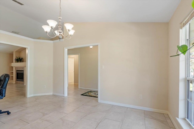 interior space with ornamental molding, a fireplace, light tile patterned floors, vaulted ceiling, and a chandelier