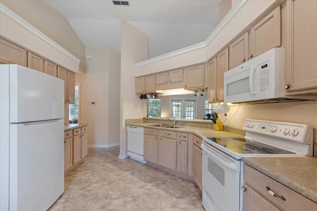 kitchen with white appliances, light brown cabinetry, lofted ceiling, and sink