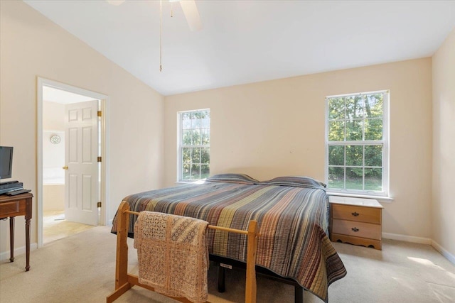 carpeted bedroom with ensuite bath, ceiling fan, multiple windows, and lofted ceiling