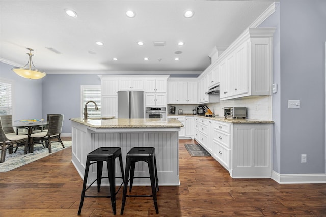 kitchen with appliances with stainless steel finishes, dark wood-type flooring, sink, a center island with sink, and white cabinetry