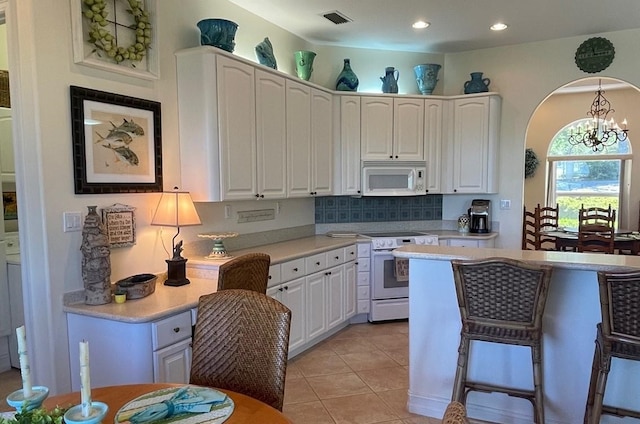 kitchen with white cabinets, arched walkways, visible vents, white appliances, and light countertops