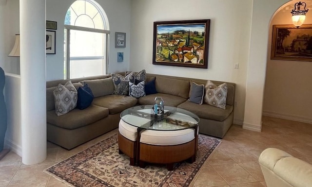 living area featuring arched walkways, baseboards, and light tile patterned floors