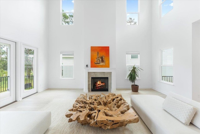 living area with a towering ceiling, a tiled fireplace, healthy amount of natural light, and wood finished floors