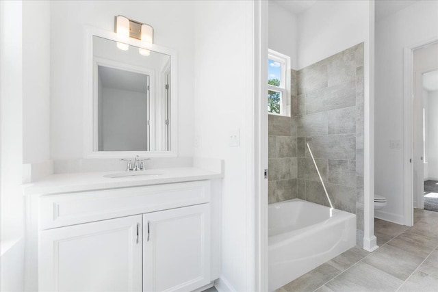 bathroom with toilet, vanity, a bathtub, and baseboards