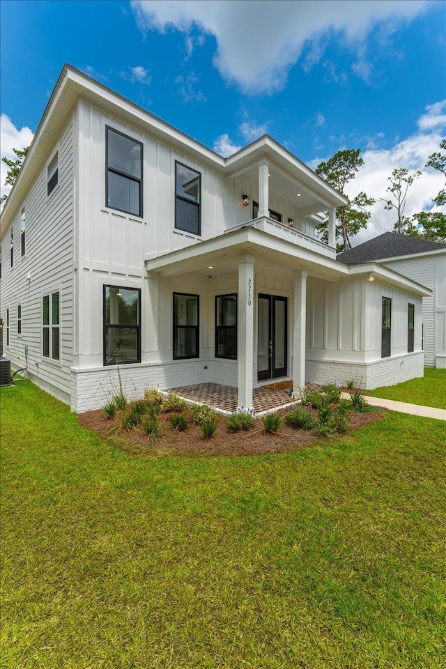 view of front of property with board and batten siding, a front lawn, cooling unit, and a balcony