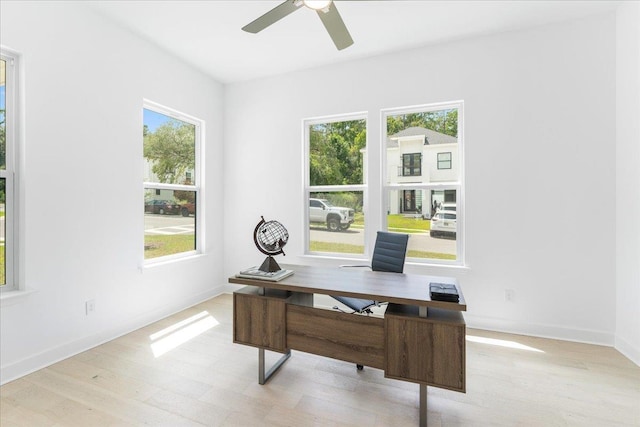 office area with a ceiling fan, baseboards, and light wood-type flooring