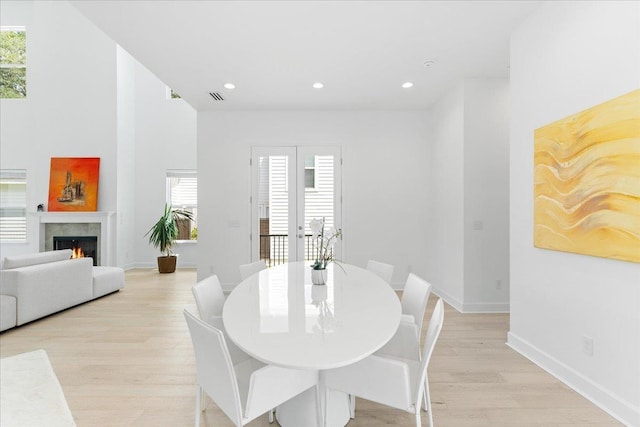 dining area featuring light wood-style floors, recessed lighting, baseboards, and a lit fireplace