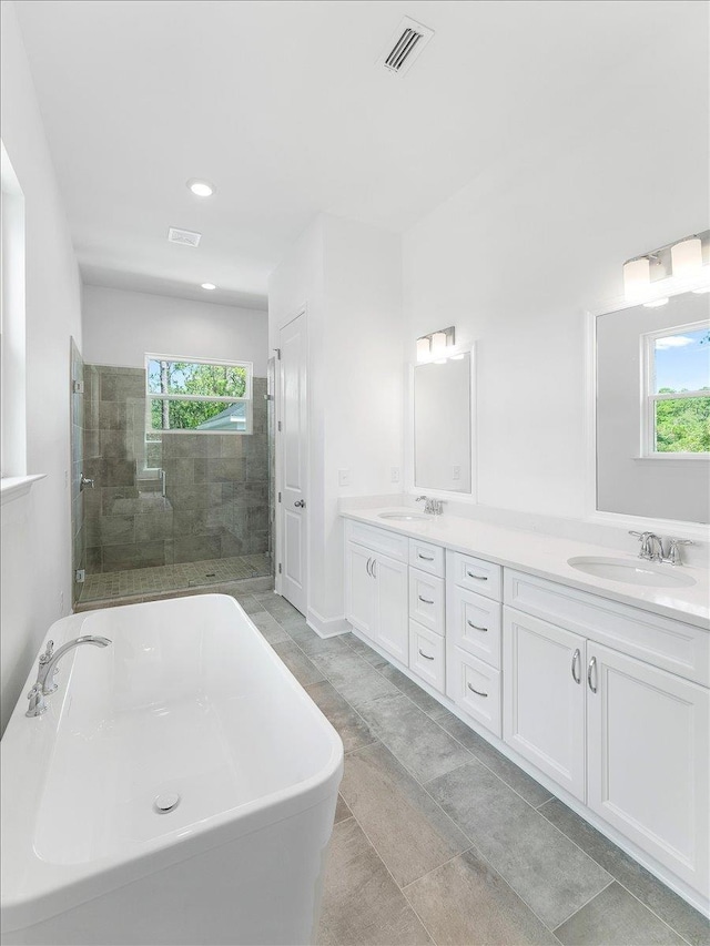 bathroom with plenty of natural light, a soaking tub, double vanity, a tile shower, and recessed lighting