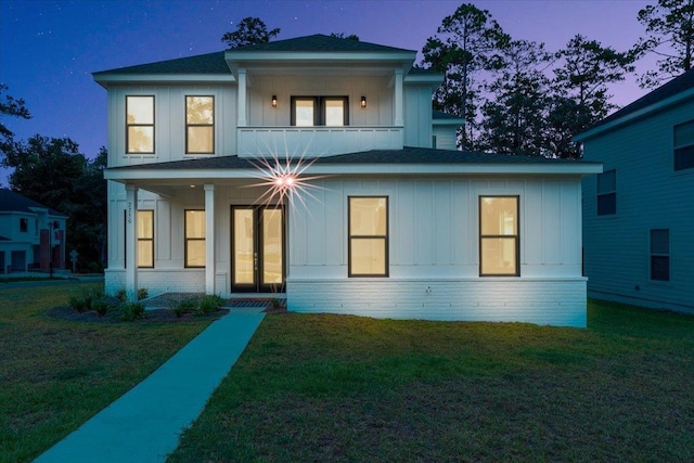 back of property featuring french doors, board and batten siding, and a lawn